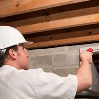 Termite inspection technician checking a basement wall and framing for termite activity in Stockton, CA